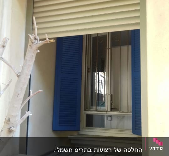תריסים כחולים פתוחים ליד חלון עם תריס גלילה